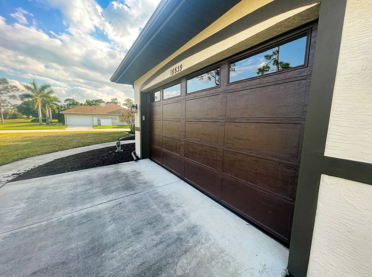 Dark wood-grain garage door with top windows installed by 941-Garage-Door on a Southwest Florida home
