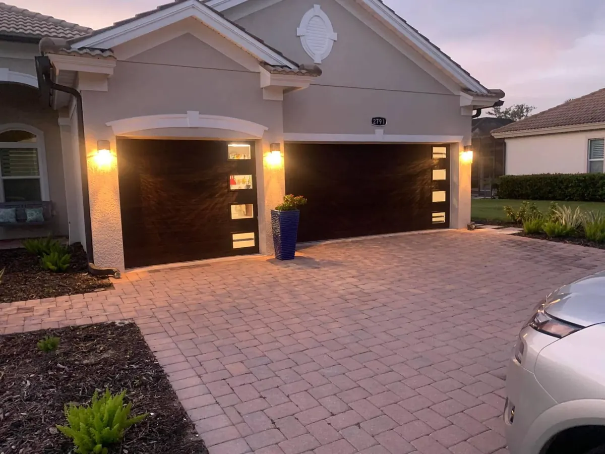 Dark wood-finish modern garage doors with vertical glass inserts installed by 941-Garage-Door at dusk in Lakewood Ranch
