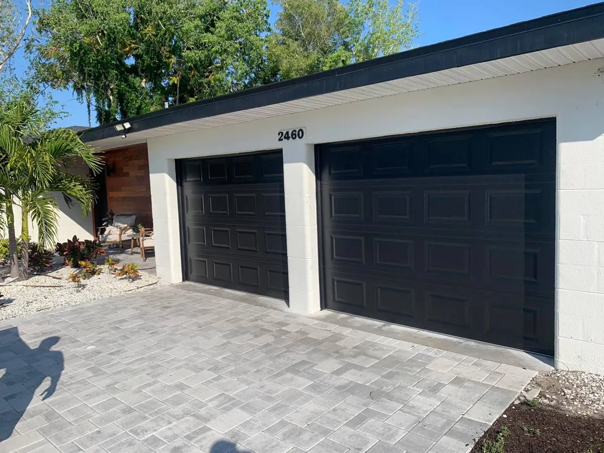 Two matte-black raised-panel garage doors installed by 941-Garage-Door on a Sarasota home with paver driveway