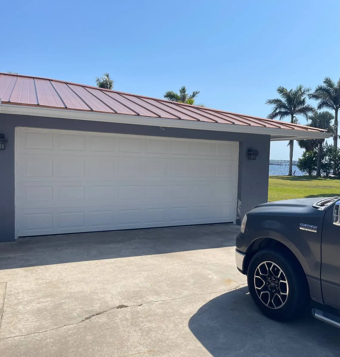 White raised-panel garage door on a waterfront Punta Gorda Isles home with copper standing-seam roof