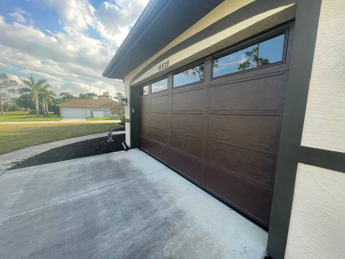 Dark wood-grain sectional garage door with clerestory window panels installed by 941-Garage-Door in Venice